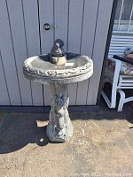 Front view of full bird bath against shed background