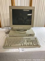 Front view of vintage Apple Macintosh Performa 6115CD desktop setup with CRT monitor, computer tower, keyboard, and mouse on a table.