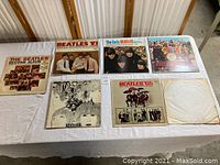 Front and back view of six Beatles vinyl album covers and one album missing cover, laid out flat on a white surface.