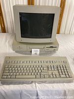 Power Macintosh 6100/66 desktop computer with CRT monitor and keyboard on table, showing front face and rainbow Apple logos
