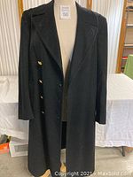 Full view of the black US Navy long wool overcoat on a dress form, showing double-breasted design and wide lapels.