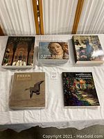 Five art books laid out on a white tablecloth showing front covers and titles