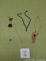 Top view of five necklaces laid out on fabric background, showing overall condition and style.