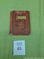 Closed book on green surface showing worn brown cover with gold title plaque 'Flowers Their Language and Poetry' and floral embossed design.