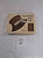 Front of the retail packaging showing the Alaska ULU Knife with walnut display stand, highlighting its legendary status.
