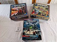 Three fantasy board games arranged on a white surface: the D&D Essentials Kit in front and the Dominion Intrigue and Dominion base game boxes behind it.