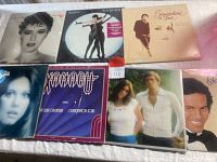 Seven vinyl record albums arranged flat on a white surface showing front covers including close-up and full-figure portraits of artists Melissa Manchester, Olivia Newton-John, The Carpenters, and others.