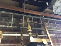 Antique wooden ladder approx. 18 feet long, wood with traditional turned wood spindle elements hung against a brick wall.