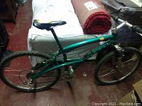Left side view of green Mrazek frame showing front suspension fork, water bottle cage and rear derailleur