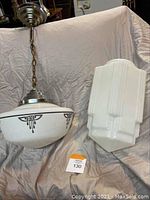 Two Art Deco light fixtures side by side on a beige cloth background, showing both the hanging globe fixture and the elongated wall sconce.