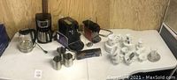 Wide angle view of all items including coffee machines, cups, pitchers and box of coffee pods