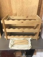 Wooden wine rack with peg dividers and separate pegs laid in a cloth pouch
