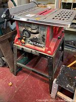 Front view of red and black Skilsaw table saw on metal stand