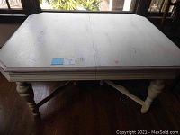 Top view of the rectangular white painted dining table with joined halves and visible wear marks.