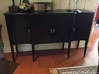 Full view of the solid wood sideboard showing four doors and slender legs.