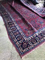 Full view of folded oriental-style area rug on concrete floor showing overall pattern and size