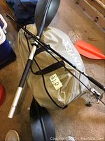 Inflatable raft in carry bag, oars, fishing rod and pump on garage floor