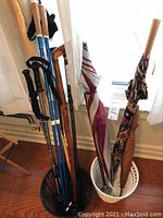Photo showing four walking sticks and canes standing in a black basket.