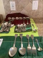 Overview of all spoons, forks and ladle laid out on red and green felt cloths