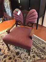 Front view of chair showing carved wood arms, mauve upholstery, and overall silhouette