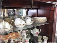Shelf view showing stacked dinner plates, luncheon plates, bread & butter plates, cups, saucers and teapot in Tranquility pattern