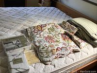 Quilt, 2 shams, duvet cover and sham laid on bed showing floral patterns and packaging