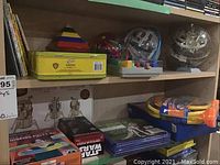 Shelf showing maze balls, 3D puzzles, putty kit, Star Wars puzzle and children's books.
