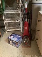 Photo showing Bissell upright carpet cleaner and Steam Bullet cleaning machine box on basement floor.