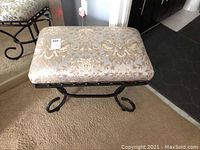 Top and front view of rectangular boudoir bench upholstered in beige and gold floral patterned fabric on black metal frame with decorative curved legs.
