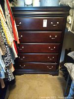 Full view of the dresser showing five drawers with metal handles and dark wood finish in a closet space.