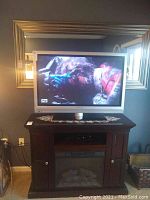 Magnavox 40-inch flat screen television on a dark wood entertainment stand showing vibrant video content.