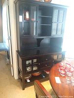 Front view of black wood Pier 1 china cabinet showing the lower and upper sections, drawers, and shelves.