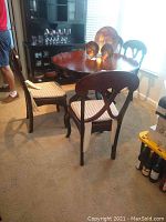 Four Pier 1 solid wood dining chairs with dark wood finish and light-colored cushioned chair pads shown around a wooden dining table.