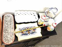 Seven Portuguese ceramics items arranged on black surface including terracotta cruet set, rectangular dish, white woven bread basket, Crate & Barrel relish tray, candy dish, Italian bread plate, and serving platter.