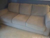 Light beige queen sofa bed with three seat cushions and three attached back cushions. Shows pet damage on one corner.