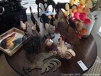 Entire lot of 11 rooster-themed items including iron, ceramic, and tin pieces arranged on table