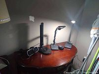 Photo showing all three task lights and the digital clock on a wooden surface against a wall, lights plugged in and turned on illuminating the wall