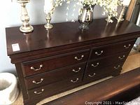 Front view of the dresser showing six drawers with handles and smooth dark wood finish.