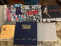 Seven items on folding table: two Dolly Parton box sets, Rolling Stones box, Bruce Springsteen box, Beatles Collection and Rarities, Chemical Guys towel