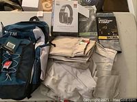 Wide view showing backpack, folded men's clothing, Monster headphone box, Beatles CD set and other items