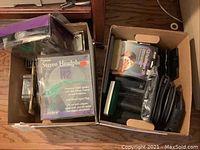 Two open cardboard boxes filled with audio accessories and media