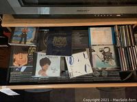 Drawer view of assorted popular artist CDs with cover art including Cher, Dionne Warwick and others.