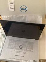 Dell laptop in original box with protective tissue sleeve and Dell logo visible