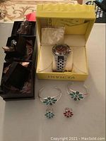 Overview of Invicta watch in yellow box, two cuff bracelets, two enamel rings, and jewelry compartment tray