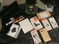 Photo showing two Invicta watches with accompanying boxes and several electronic accessory boxes arranged on black surface.