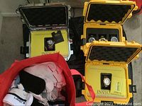 Four Invicta hard watch cases (three yellow, one silver) and a red bag of socks