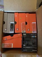 Overhead view of a cardboard shipping box containing six Nike sneaker boxes and one Sony radio box