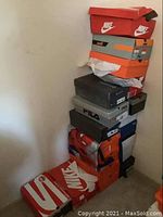 Stack of approximately nine sneaker boxes showing Nike, Fila, Rockport and other brands