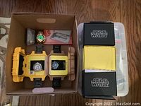 Cardboard box holding two yellow micro cases with latches, two black SW boxes and white compartment tray