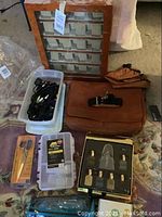 Overview of lot showing watch display case, Kenneth Cole leather bag, plastic containers with cords, fragrance set, and other items.